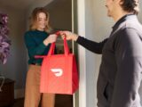 a woman holding a red shopping bag while standing next to a man