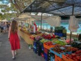 woman walking beside fruit and vegetable vendors