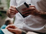 man in white button up shirt holding black and white box