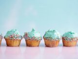 six teal icing cupcakes with sprinkles