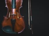 brown violin with bow in black background