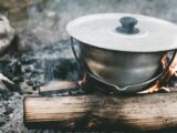 a pot sitting on top of a fire next to a log