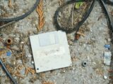 an old computer sitting on the ground surrounded by wires