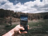 a person taking a picture of a field with a cell phone