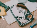 Close-up of a disassembled hard drive showing internal components on a wooden table.