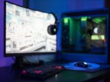 High-tech gaming setup featuring a curved monitor, RGB keyboard, and vibrant lighting.
