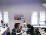 A group of people discussing ideas around laptops in a bright, modern office space.