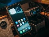 Smartphone and digital charging station on a desk with Klipsch speaker visible.