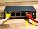 Close-up of a TP-Link Ethernet switch with yellow, red, and white cables connected.