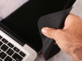 a hand holding a cloth over a laptop