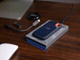 A SanDisk SSD with USB accessories on a wooden desk, showcasing portable technology storage solutions.