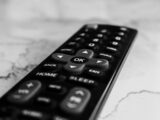 A black remote control rests on a marble surface.
