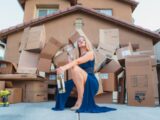 woman in blue dress holding brown cardboard box