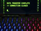Close-up of a RGB lit keyboard with a screen displaying 'Data Transfer Complete'.