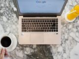 Top view of a laptop workspace with coffee and orange juice on a marble table. Perfect for productivity themes.