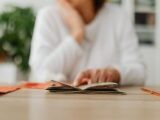 A woman sitting at a desk sorting through cash, focusing on household budgeting.