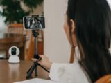 A woman making a video call on a smartphone using a cellphone stand indoors.