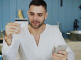 Man holding credit card and smartphone, shopping online at home.