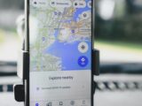 A smartphone displaying GPS map of New York City secured in a car mount during daylight.