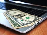 Close-up of US dollar bills placed on a laptop symbolizing digital finance and economy.