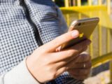 Close-up of a young adult using a smartphone outdoors, highlighting modern technology and connectivity.