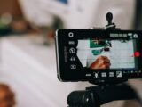 Smartphone on tripod capturing person writing on paper, showing content creation process.