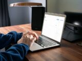 person using macbook pro on brown wooden table