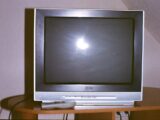A television set with a remote control on a table.