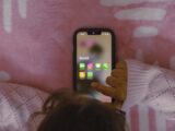 a person laying in bed holding a cell phone