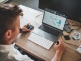 man holding mouse and iPhone while using Macbook Pro