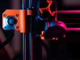 A detailed close-up of a 3D printer showcasing its extruder and components under vibrant lighting.