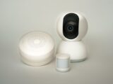 Modern smart home devices including a camera and sensors on a neutral background.