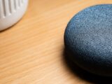 A close-up view of a smart speaker on a wooden table, capturing texture details.