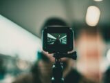 A focused action camera recording a vlogger at a train station with blurred background.