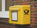 yellow mailbox on brown wall bricks