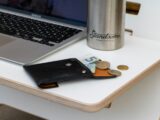 a wallet sitting on a table next to a laptop