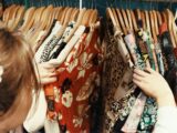 person holding assorted clothes in wooden hanger