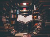 view of floating open book from stacked books in library