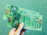 person holding two 20 Canadian dollar banknotes