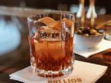 clear drinking glass with brown liquid on white ceramic saucer
