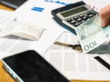 Close-up of financial documents, calculator, and Polish Zloty currency on a desk.