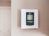 Close-up of a modern digital thermostat mounted on a wall, displaying temperature settings in Celsius.