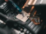 a close up of a person holding a pen near a computer motherboard
