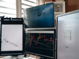 A home office setup featuring multiple monitors displaying trading charts and data analysis.