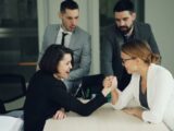 Colleagues engaging in a spirited arm wrestling contest at work, showcasing teamwork and competition.