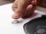 Detailed shot of a thumb creating a fingerprint on white paper, ideal for security themes.
