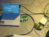 An overhead view of a vintage electronics setup featuring a laptop and disks with tangled cables.