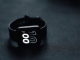 Modern smartwatch displaying time on a sleek dark gray surface, perfect for tech enthusiasts.