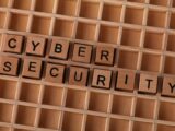 Wooden letter blocks spelling 'CYBER SECURITY' on a wooden grid background for data protection themes.