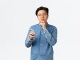 A man in a blue shirt is holding a cell phone